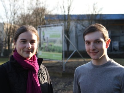 Zwei junge Menschen, die ihr FÖJ bei der Erdgas Südwest absolvieren, stehen vor einem Werbeplakat der Erdgas Südwest