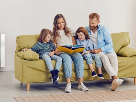Familie auf der Couch sitzend in ihrem warmen Zuhause und im Hintergrund heizt die Heizung