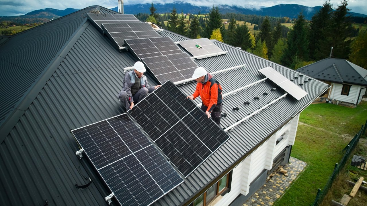 Solarteure installieren eine Solaranlage auf dem Dach eines Einfamilienhauses.