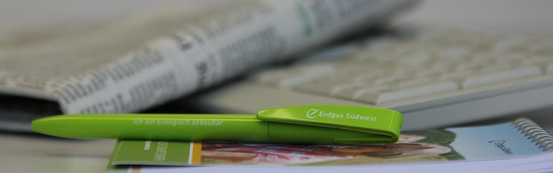 grüner, biologisch abbaubarer Kugelschreiber der Erdgas Südwest vor einer Zeitung