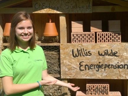 Eine junge Frau, die ihr FÖJ bei der Erdgas Südwest absolvierte, steht vor einem der vielen Wildbienenhotels der Erdgas Südwest. Dieses trägt den Namen "Willis wilde Energiepension"