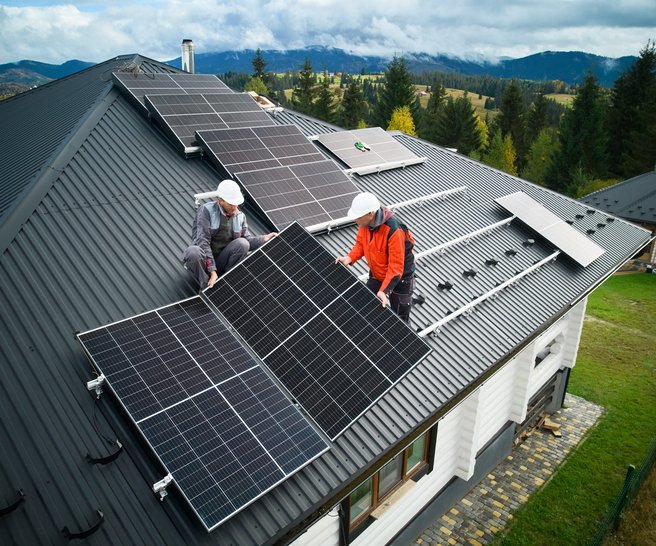 Solarteure installieren eine Solaranlage auf dem Dach eines Einfamilienhauses.