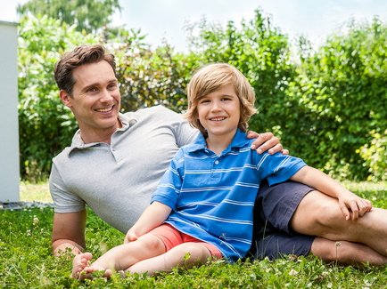 Vater und Sohn sitzen im Garten auf dem Rasen