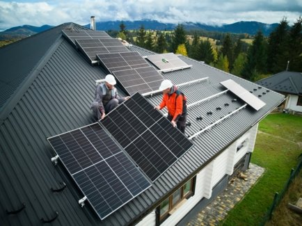 Solarteure installieren eine Solaranlage auf dem Dach eines Einfamilienhauses.