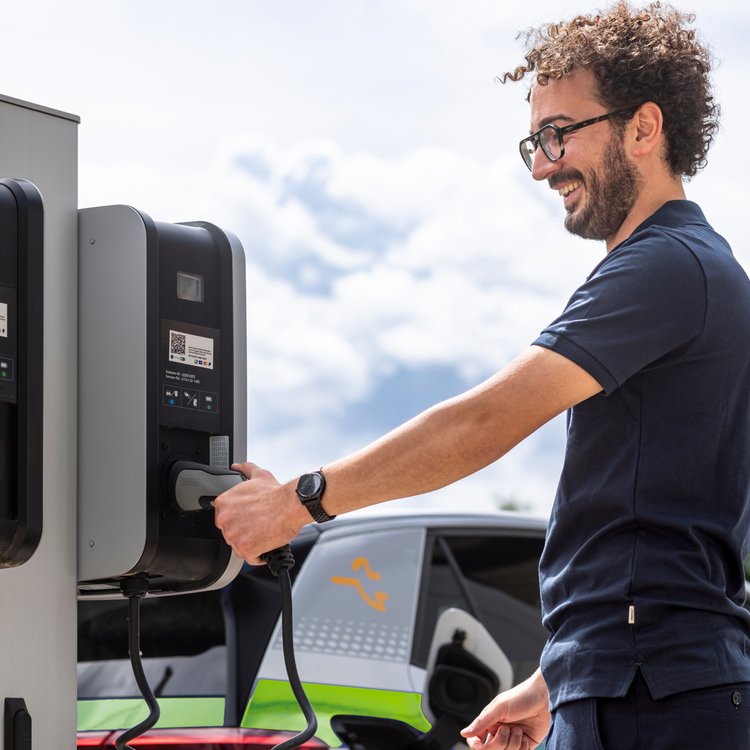 Zwei Ladestationen der Erdgas Südwest. Ein Kunde steckt Ladestecker seines E-Autos in die Ladesäule.