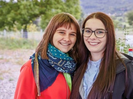 Zwei junge Frauen, die ihr FÖJ bei der Erdgas Südwest absolvieren, stehen vor einer großen Grünfläche