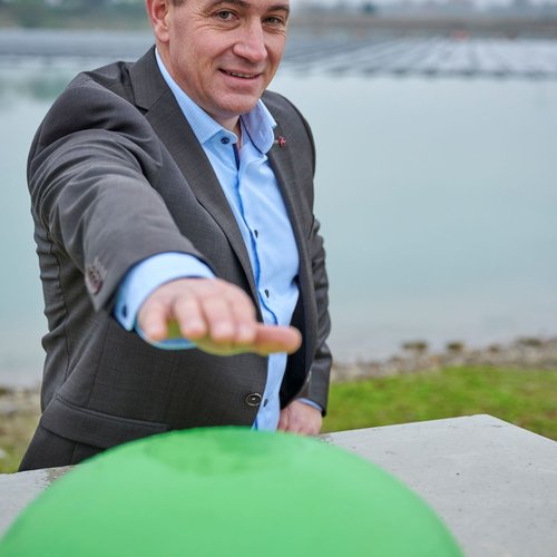 Man sieht einen Mann vor der schwimmenden PV Anlage